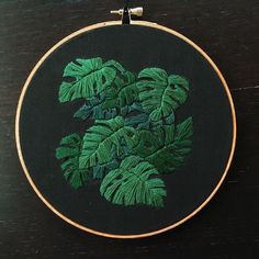 a close up of a embroidery on a wooden table with a plant in the middle