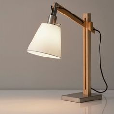 a desk lamp with a white shade on it's side and a black cord attached to the base