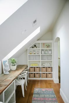 a room with a desk, shelves and baskets on the floor in front of it