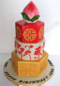 a three tiered cake decorated with red and gold decorations