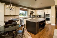 a large kitchen with an island in the middle and chairs at the table on the other side