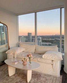 a living room filled with furniture and large windows overlooking the cityscape at sunset