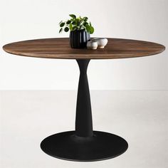 a round wooden table with two black vases on top