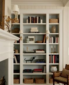 a white bookcase filled with lots of books next to a fire place in a living room