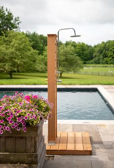 a wooden planter filled with flowers next to a swimming pool