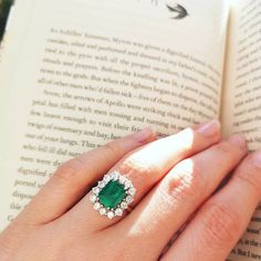 a close up of a person's hand holding an open book with a ring on it