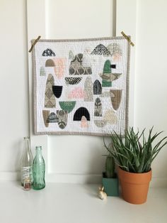 a potted plant sitting on top of a white table next to a wall hanging