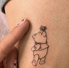 a woman's stomach with a small tattoo of a winnie the pooh character on it