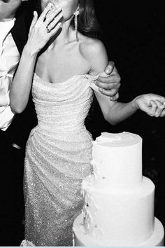 a man and woman standing next to each other in front of a cake