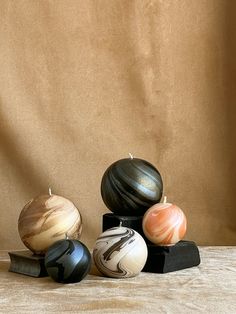 four marbled balls sitting on top of each other in front of a brown background