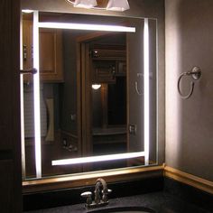 a bathroom sink with a lighted mirror above it