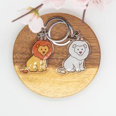 two keychains with lions on them sitting next to a cherry blossom branch in front of a white background