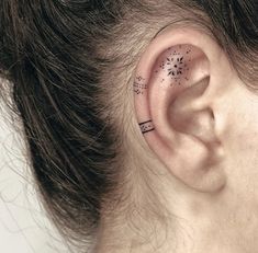 a woman's ear with small stars on the top and behind her ear,