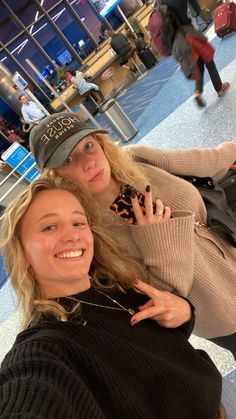 two women are posing for the camera in an airport with their arms around each other