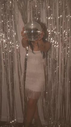 a woman standing in front of a mirror holding a disco ball