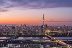 an aerial view of a city at night with the sun setting in the distance and lights on