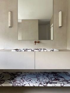 a modern bathroom with marble counter tops and mirrors