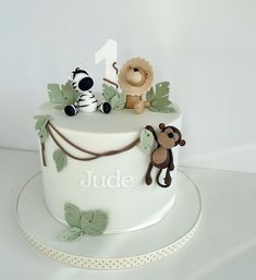 a white cake decorated with jungle animals and leaves