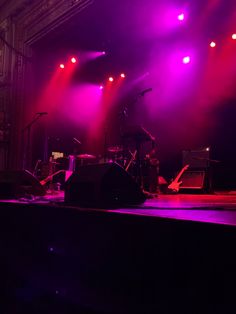 the stage is lit up with purple and red lights as well as musical instruments on it