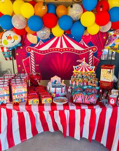 a circus themed birthday party with balloons, candy and treats on a table in front of a carnival tent