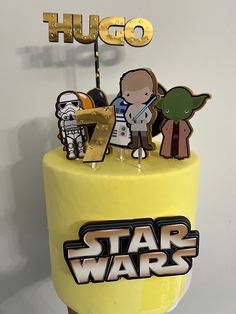 a yellow cake with star wars characters on it and the word hug spelled in gold letters