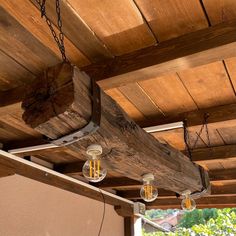 some lights hanging from a wooden beam on the ceiling in an outdoor area with wood planks