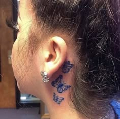 a woman's ear with butterflies on it and behind her ear is a tattoo