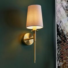 a wall light that is on the side of a wall next to a painting and lamp shade