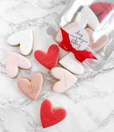 heart shaped cookies in a bag on a marble counter top with a red ribbon around them