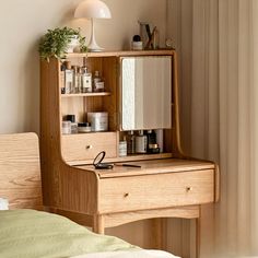 a small wooden desk with a mirror on top of it next to a bed in a room