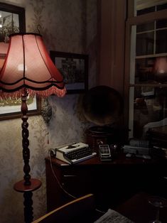 a lamp sitting on top of a wooden table next to a desk with a typewriter