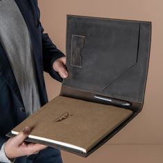 a man in a suit holding an open book with a pen on the cover,