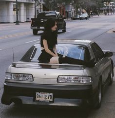 a woman sitting on the hood of a car