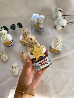 a person holding a jar of peanut butter with teddy bears around it on a table