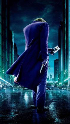 the dark knight rises movie poster with joker in purple coat and black gloves standing on city street