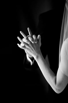 black and white photograph of a bride holding her hands out to the side in prayer