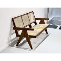 a wooden bench sitting in front of a window next to a white wall and floor