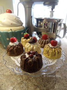 four cakes on a glass plate sitting on a counter