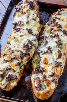 two pieces of bread sitting on top of a baking pan covered in cheese and toppings