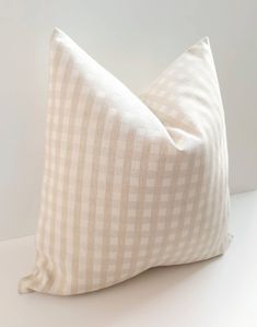 a white and beige checkered pillow sitting on top of a table next to a wall