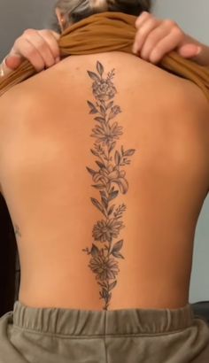 the back of a woman's body with flowers on it and leaves coming out of her lower back