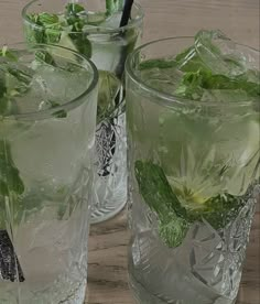 two glasses filled with ice and green leaves