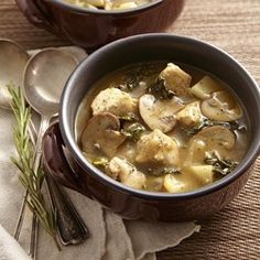 two bowls filled with soup on top of a wooden table next to silver spoons