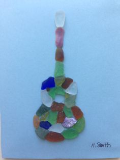 a colorful guitar made out of sea glass on a blue paper with the words h smith written below it