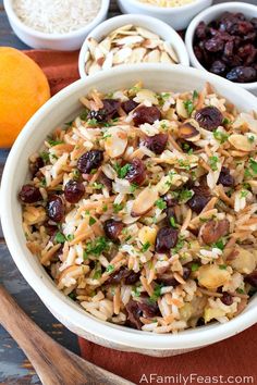 a white bowl filled with rice and raisins next to bowls of oranges