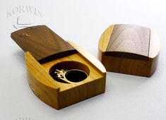 a wooden box with a ring in it on top of a white table next to another box