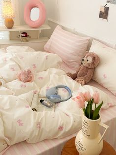 a teddy bear sitting on top of a bed covered in white sheets and pink flowers