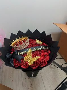 a birthday cake that is on top of a box with roses and a tiara