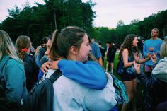 two girls hugging each other in the middle of a crowd