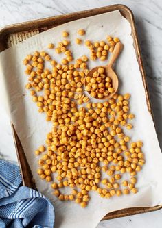 chickpeas are scattered on a baking sheet with a wooden spoon and blue napkin